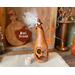 This shows a carved pumpkin ghost with candle. It is a dried gourd with a silly ghost face. The top has white hair, dried berries and bones.